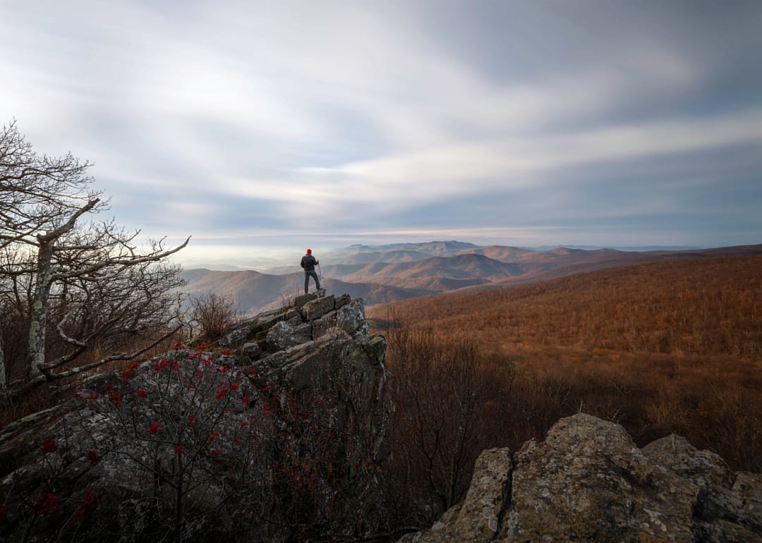 A hiker on top of the mountain taking in the views of surrounding mountains.