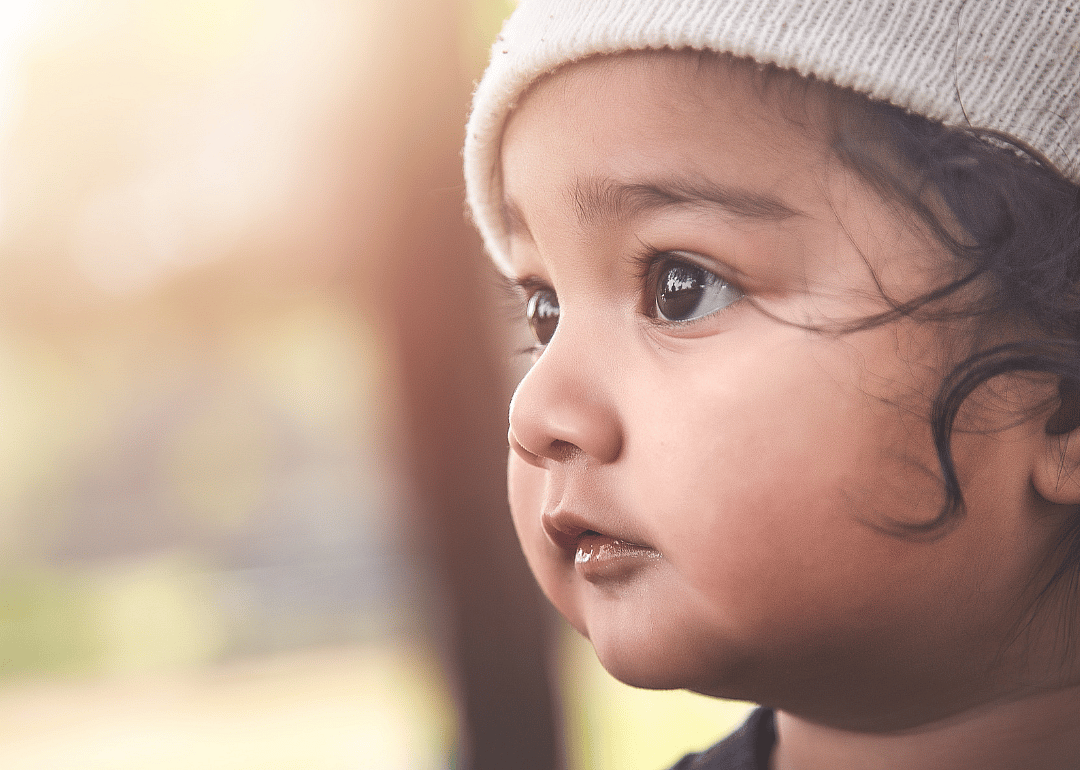 A closeup of an Asian / Indian boy wearing a hat.