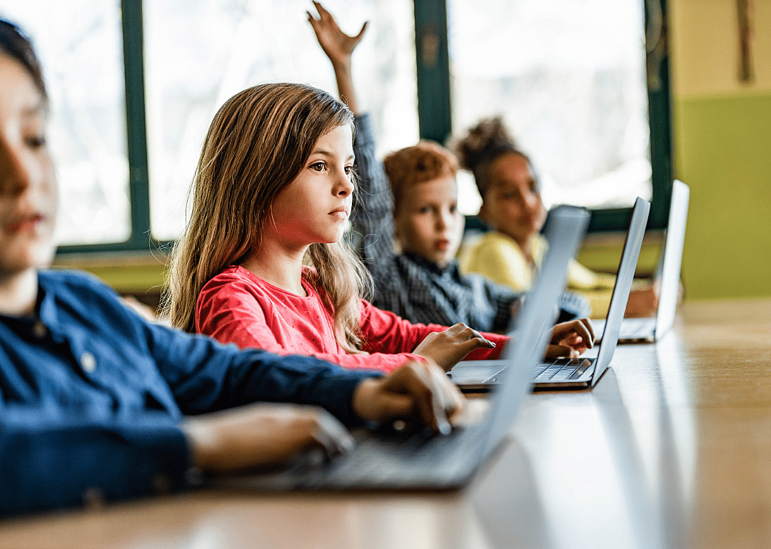 Young children in a classroom setting with laptops.