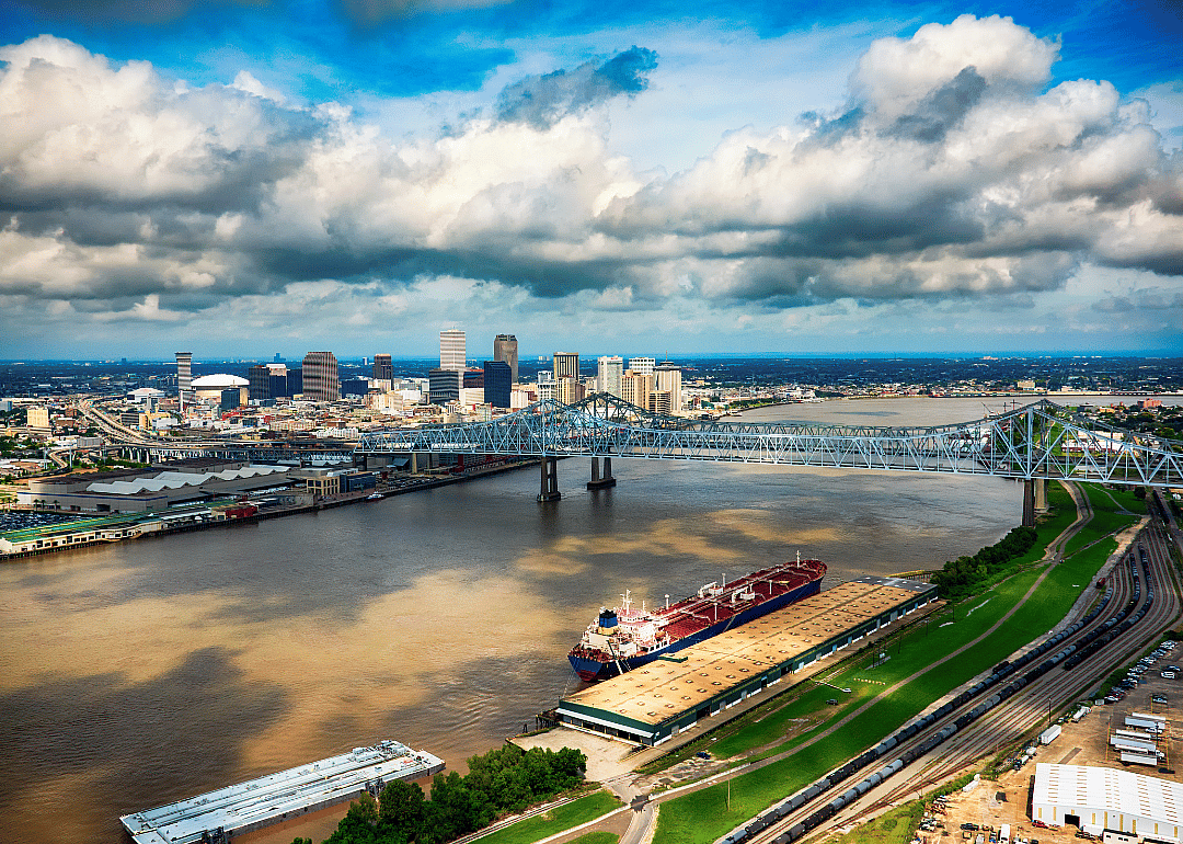 City skyline by the wide river and iron bridge in the foreground.