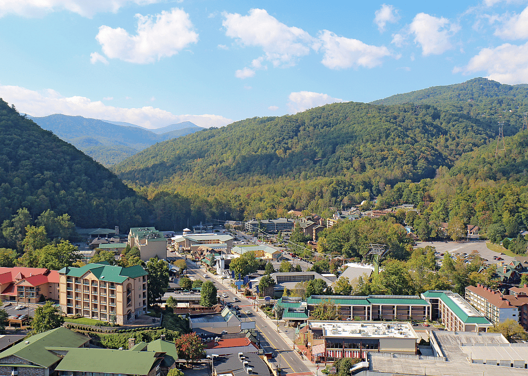 Main road in a small town with tree-covered mountains surrounding it.