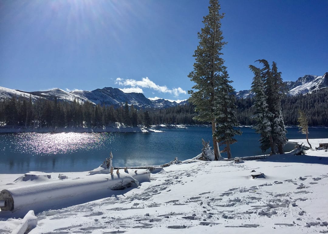 A blue lake in winter surrounded by the mountains.