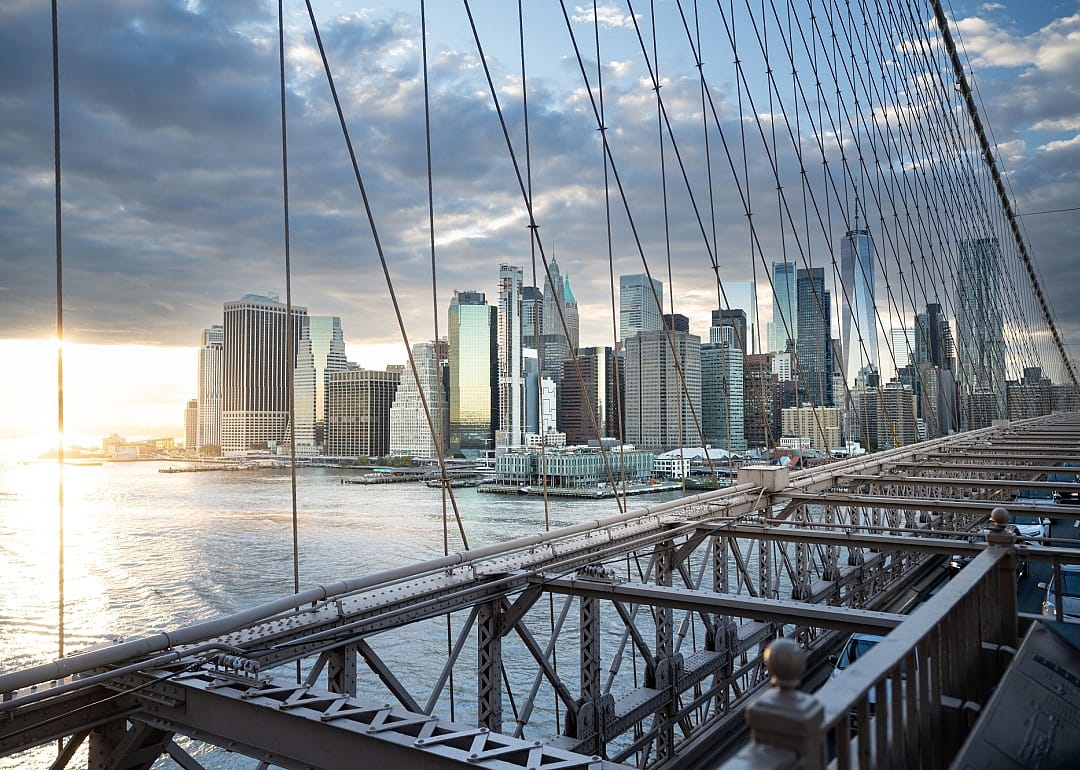 A view of a suspension bridge and a cityskyline at sunset. 