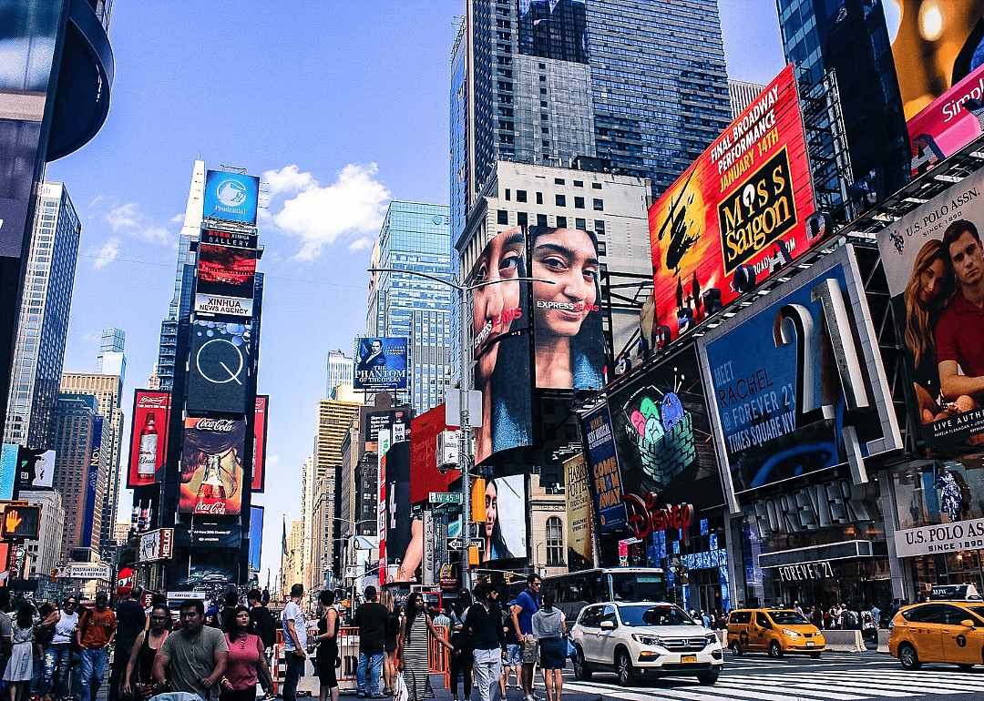 Tall skyscrapers with colorful ads, traffic and crowds of people.