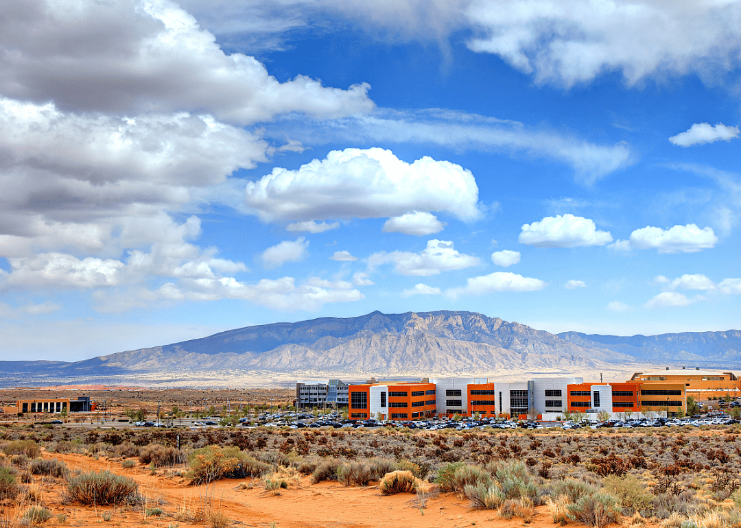 Modern buildings in vast barren land with tall mountains in the background.