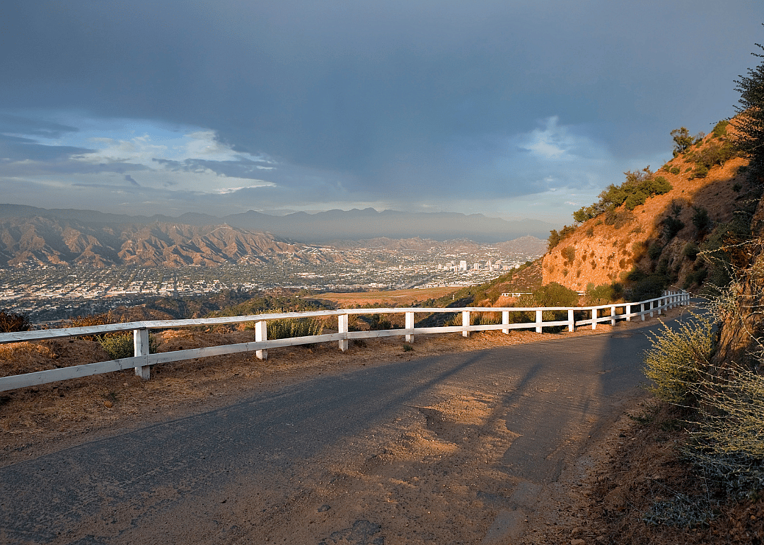 A white fence on a mountain road with Glendale in the distance.