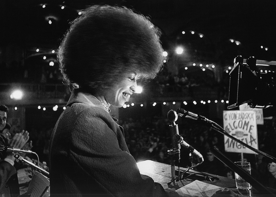 Angela Davis seated on stage, smiling as people clap for her. 