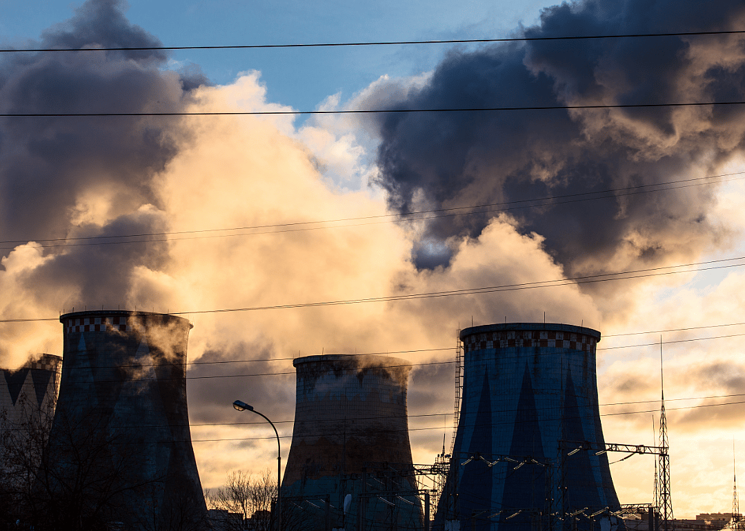 Smokestacks emanating pollutants at sunset.