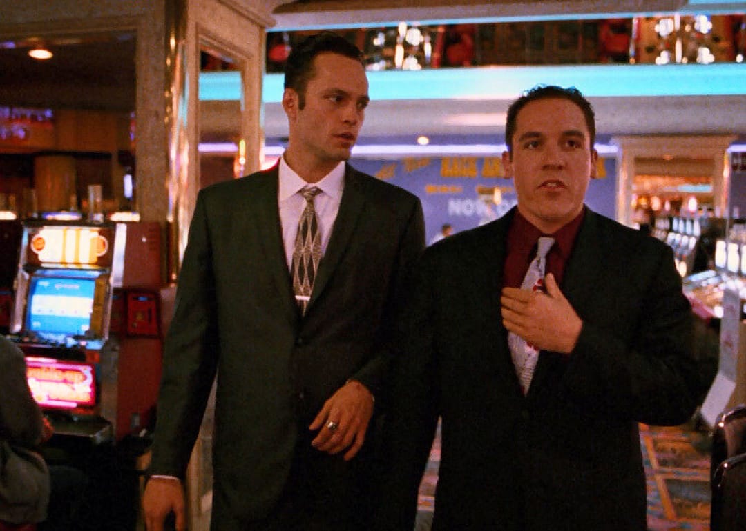 Vince Vaughn and Jon Favreau in suits walking through a casino.