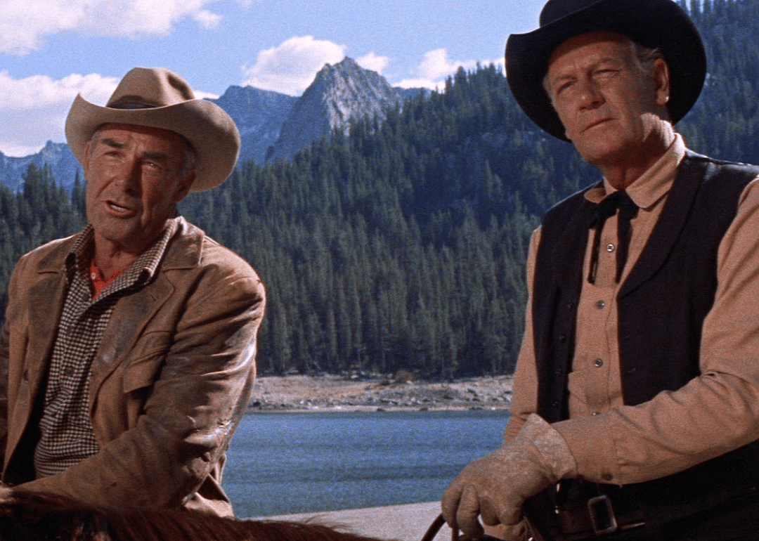 Two cowboys on horseback in the mountains.