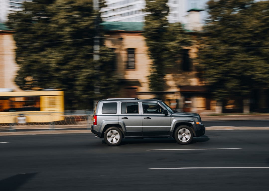 A gray Jeep Patriot speeding down a highway.