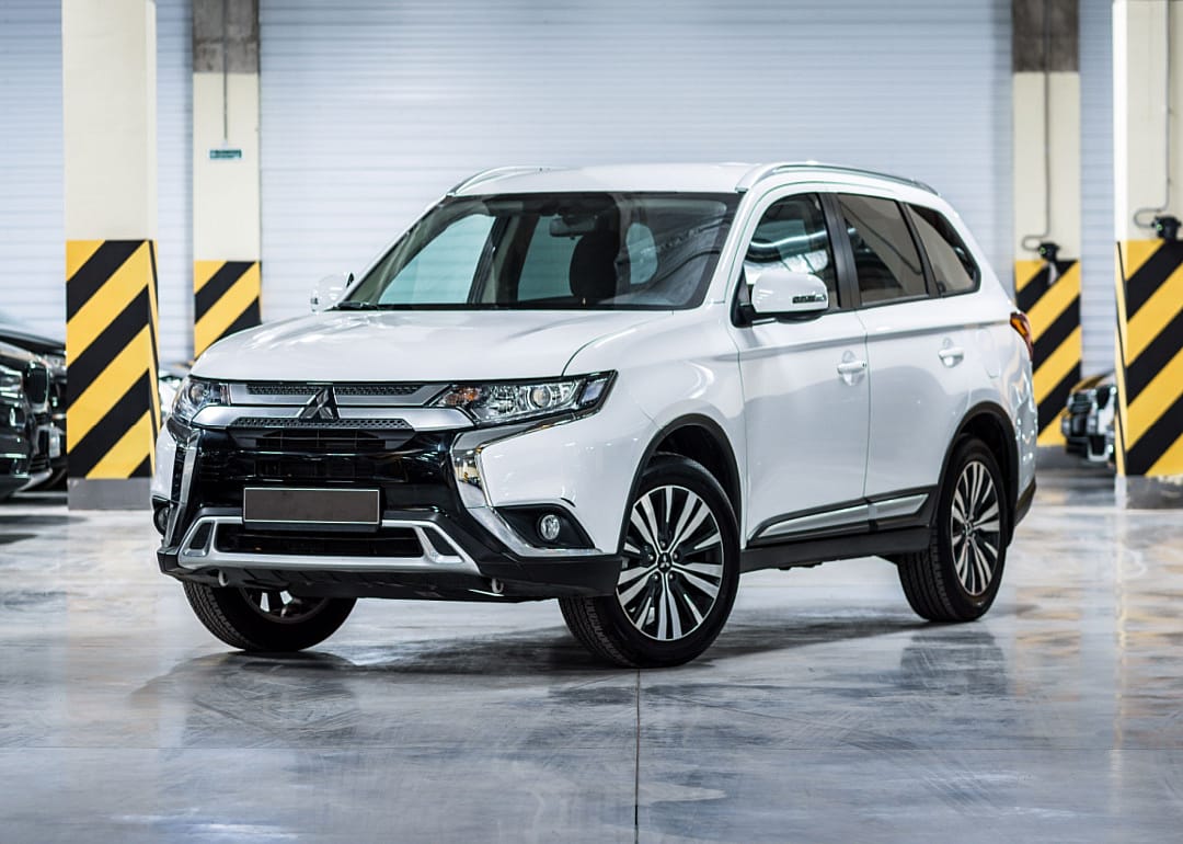 A white Mitsubishi Outlander in a warehouse.