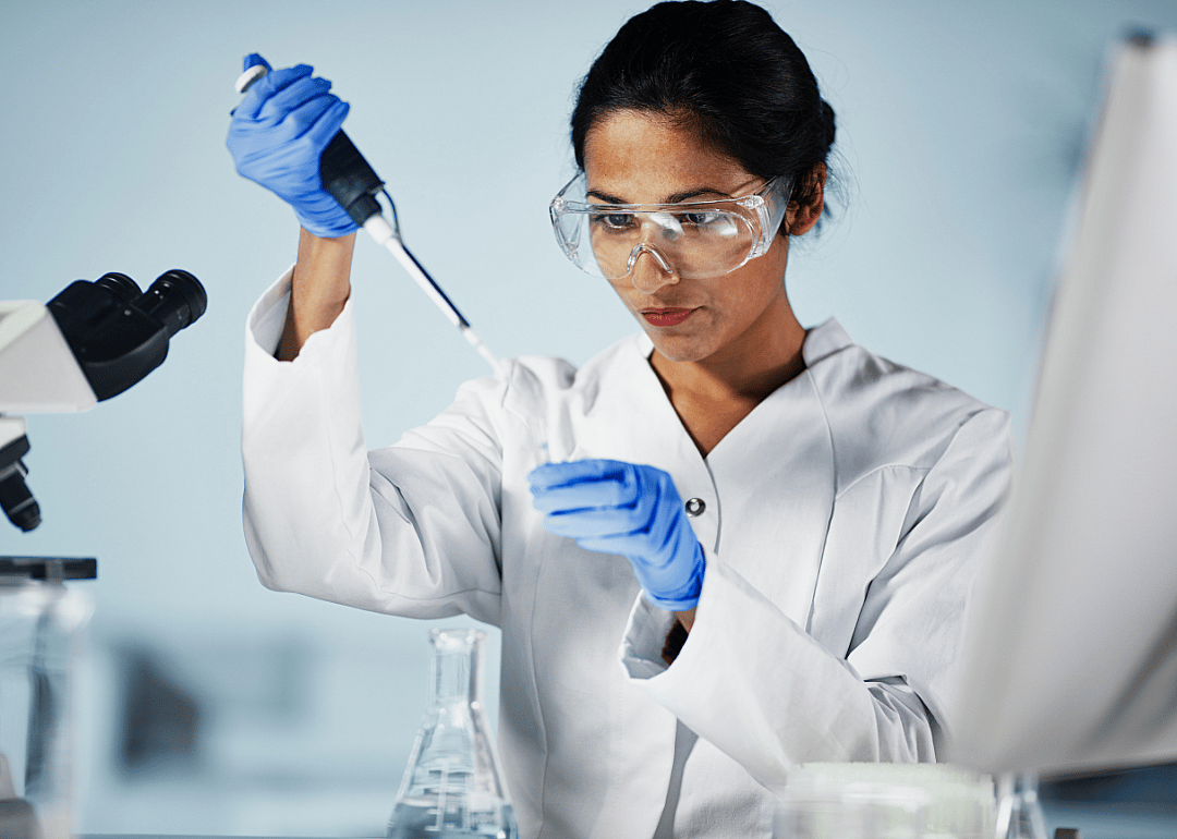 A scientist in a lab looking at specimen in front of her. 