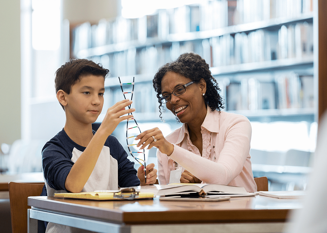A science teacher providing guidance to a young boy sitting next to her.
