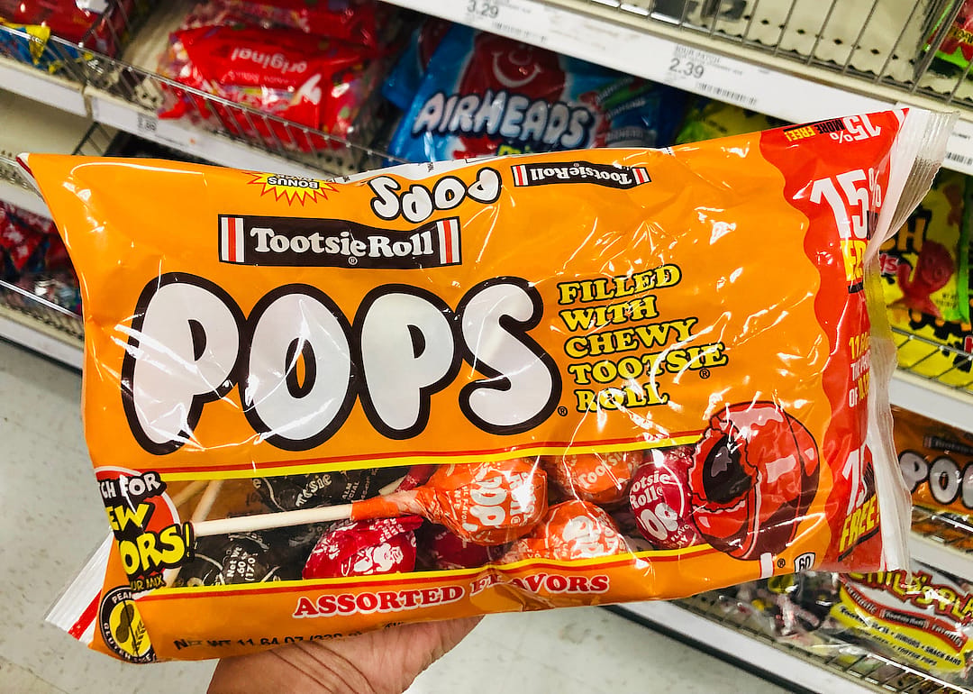Hand holds up a package of Tootsie Pops.