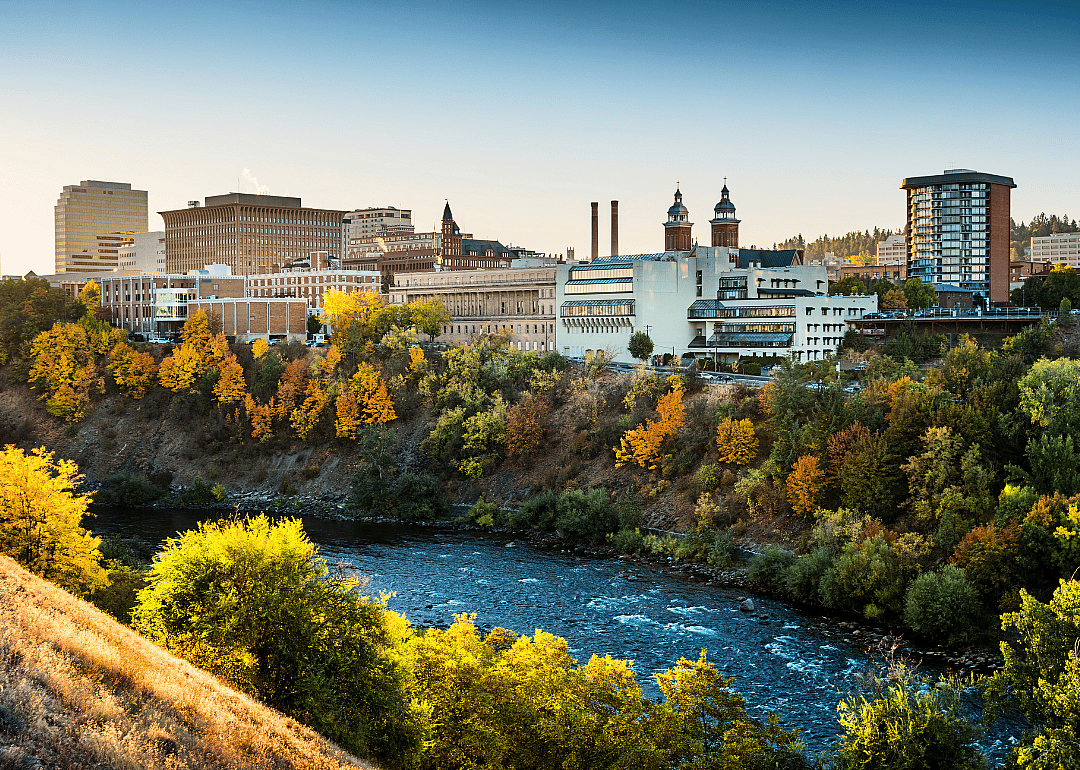 A city skyline situated on the hill with a river in the foreground.