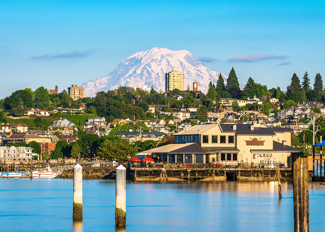Homes and businesses going up a large hill with snowy mountains in the background.