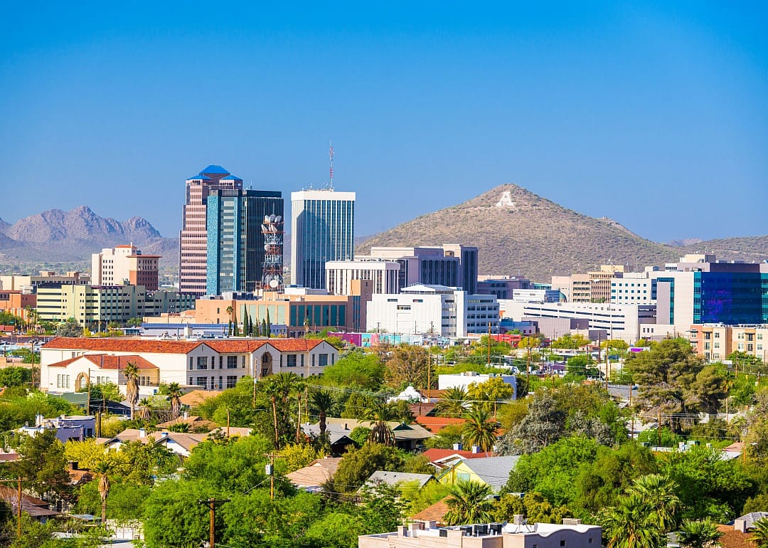 A city with a mix of building heights, from low-rise residential areas to taller office buildings in the downtown area. A mountain peak rises in the background.