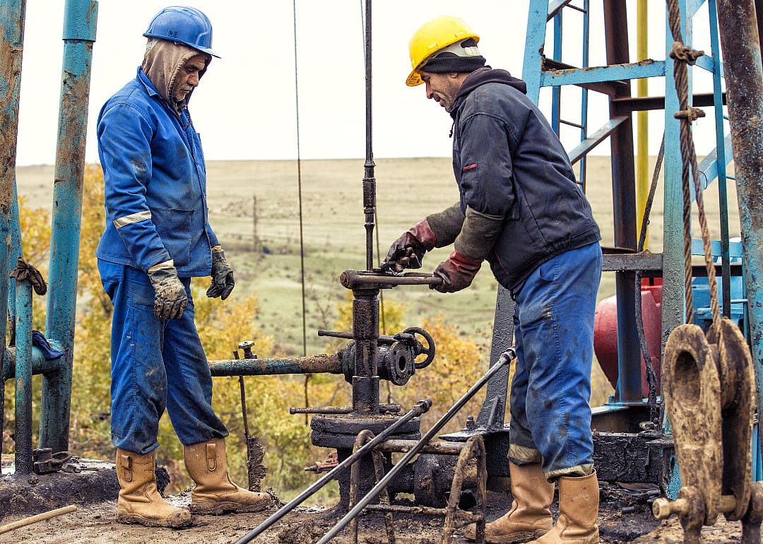 Two roustabouts checking an oil pump.