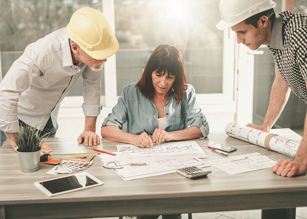 A group of architects looking over designs at a desk.