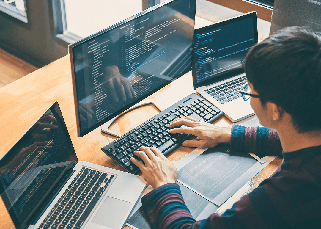 A web developer with two laptops and a separate monitor.