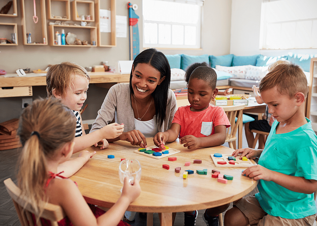 A tutor working with a group of four kindergarten students on identifying shapes.