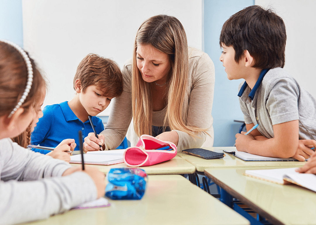 A teacher tutoring a group of four elementary-aged students.