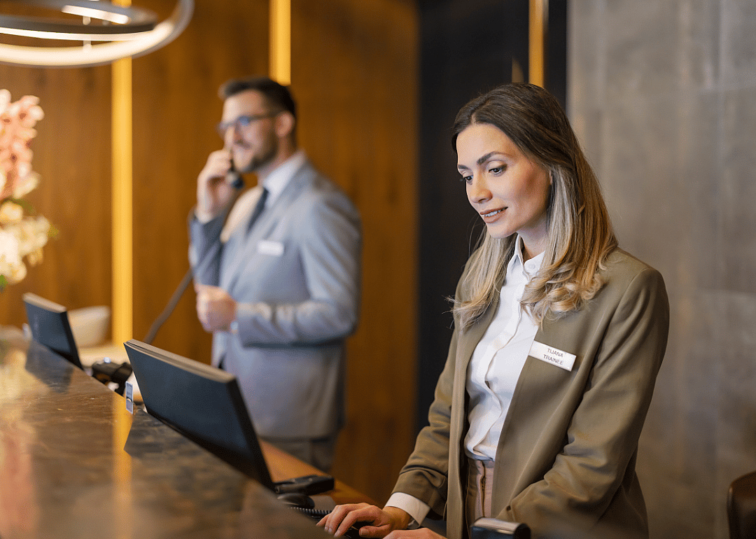 Two concierges working behind the desk at a hotel.
