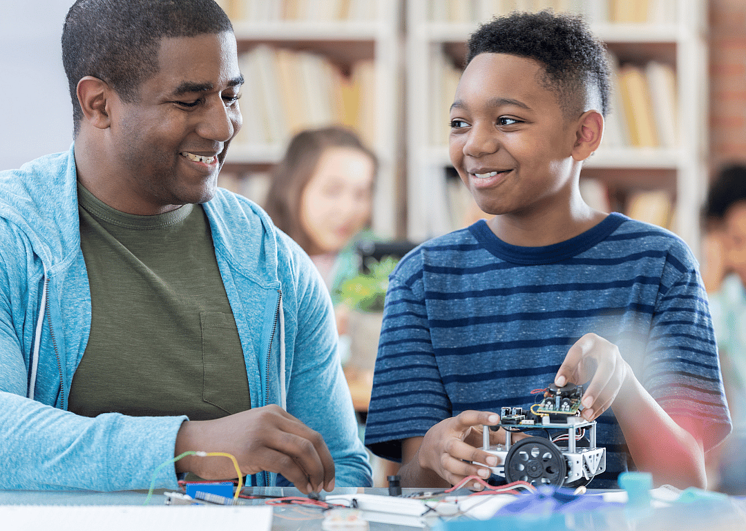 A mentor and junior high student discussing a robotics project and laughing