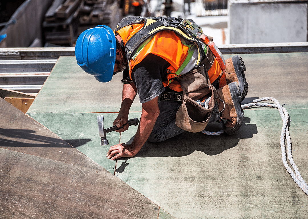 Construction worker nails a piece of wood
