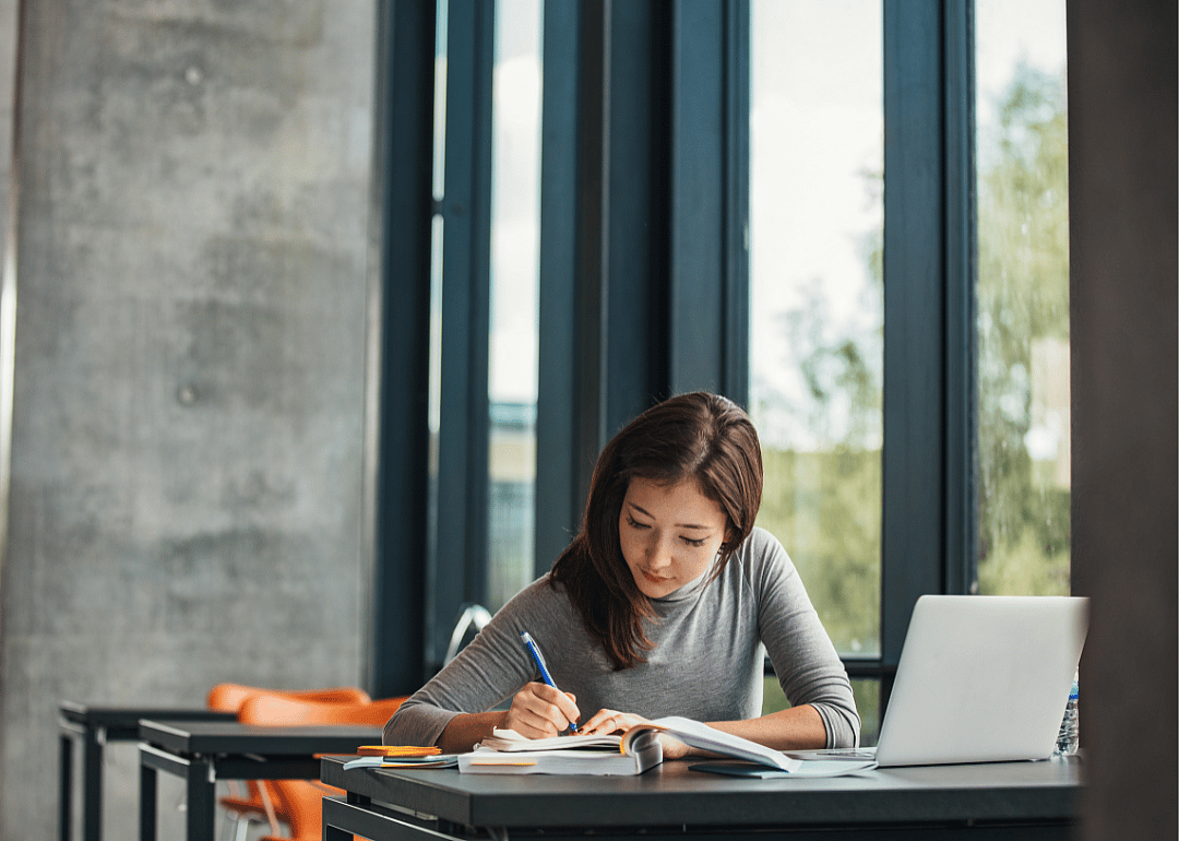 A student taking notes in a college classroom.
