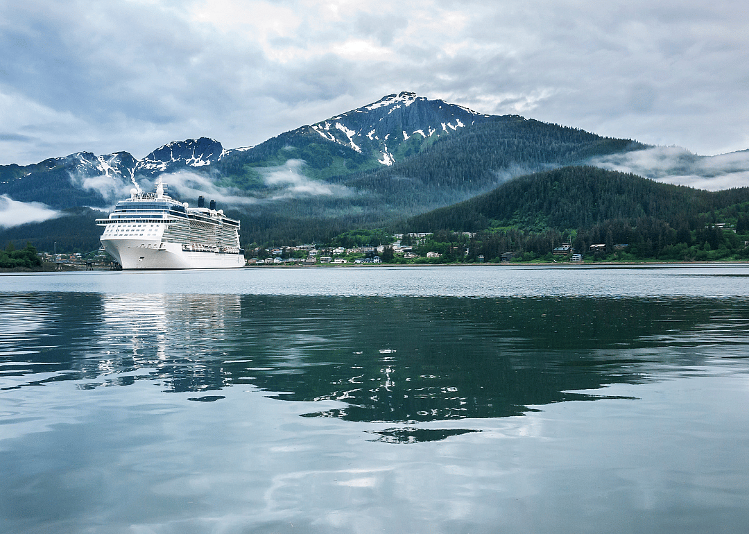 A cruise ship at a port in Juneau with a snow capped mountain and low-lying fog in the background.