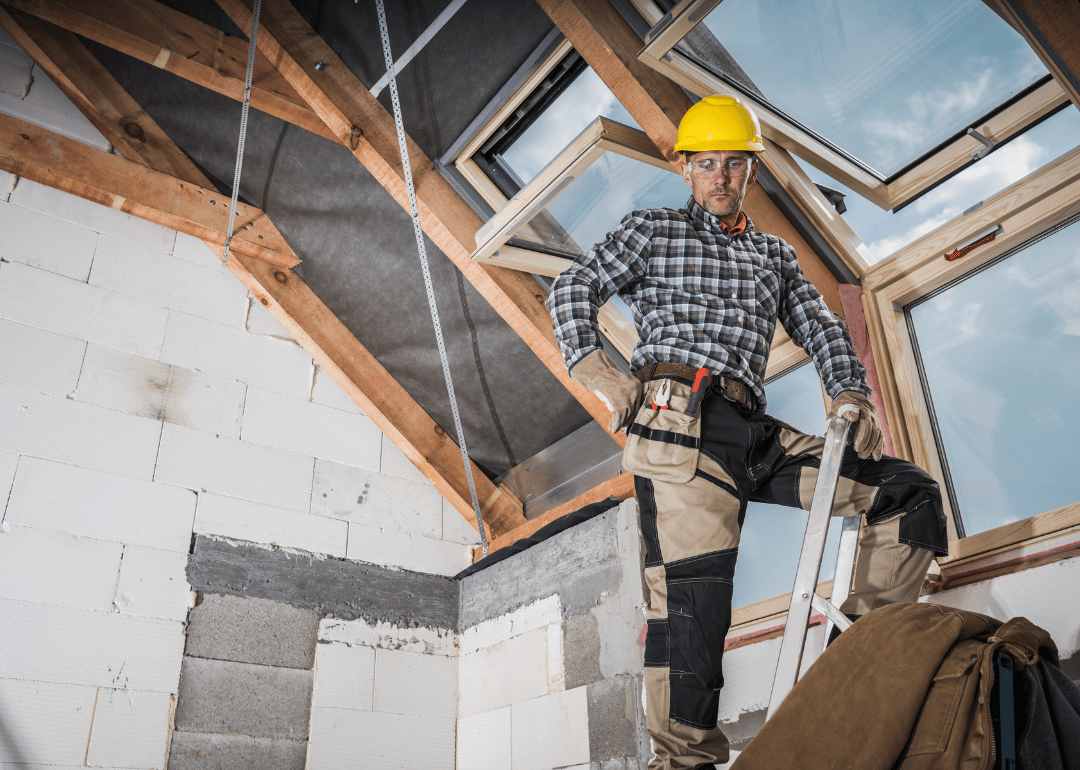 A construction worker installing a skylight in a house.