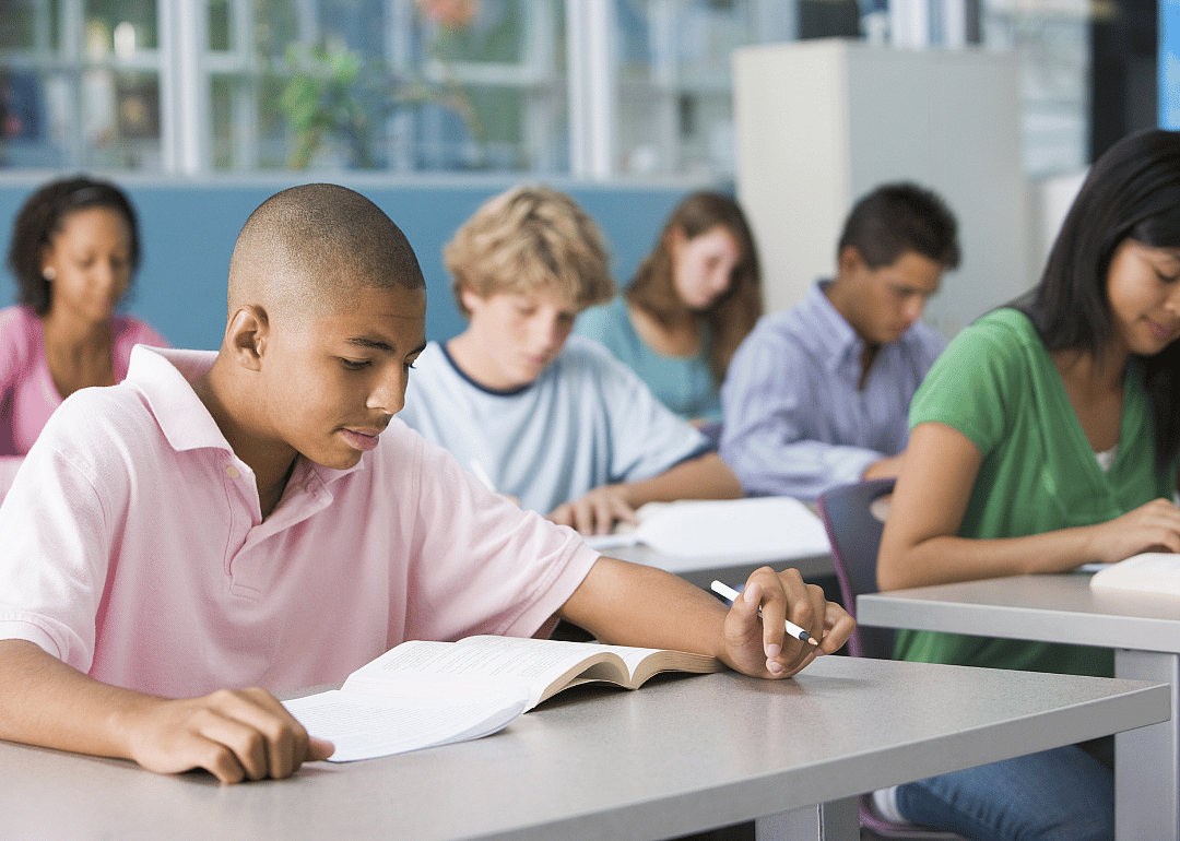 Students writing at their desks in class.