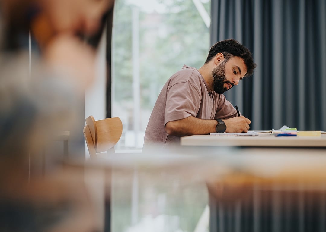 A college student intently writing in a classroom.