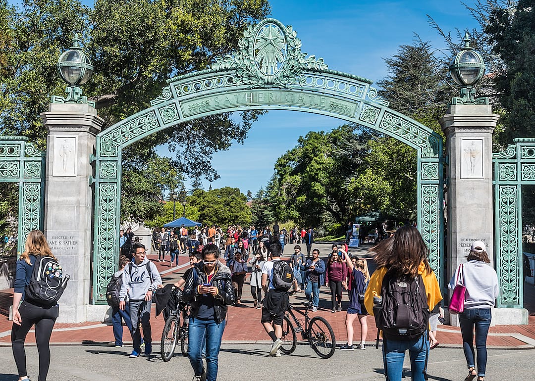 Young people going under a green arch.