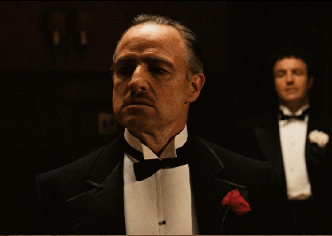 Marlon Brando in a suit with a red rose boutonnière.