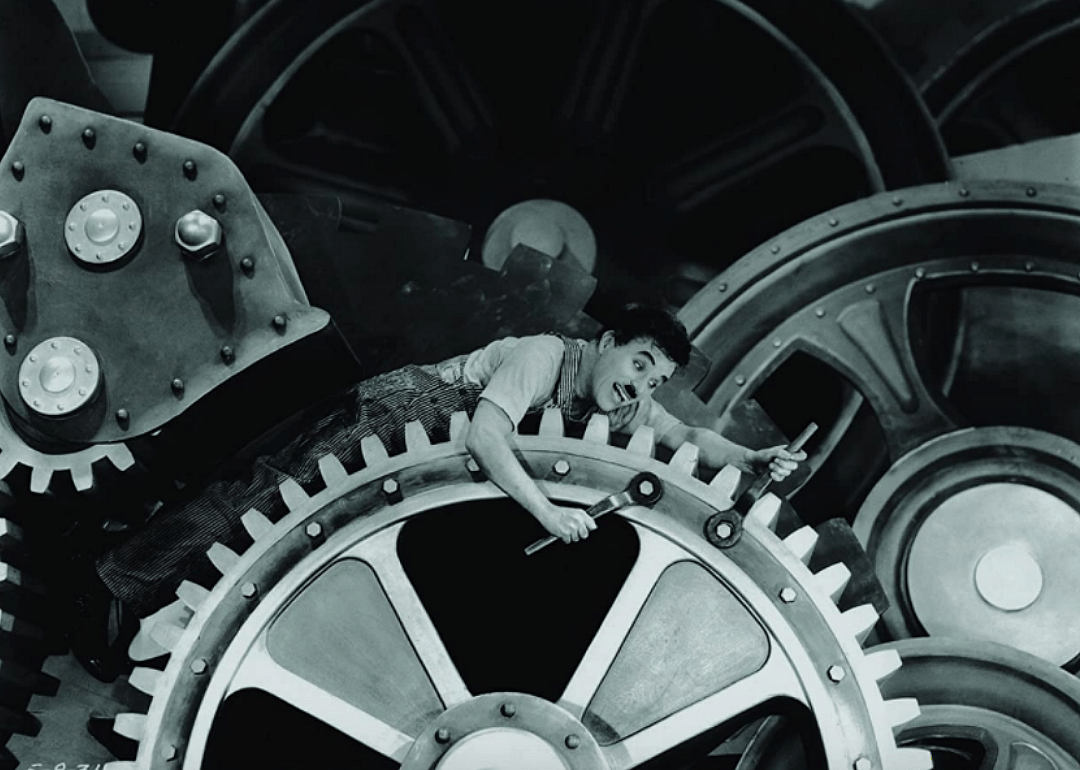 Charles Chaplin inside the wheels of a machine.