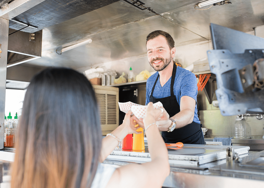 Short-order cook hands food to a customer.