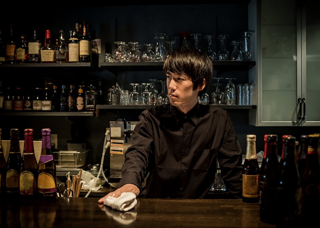 A bartender washes a counter top.