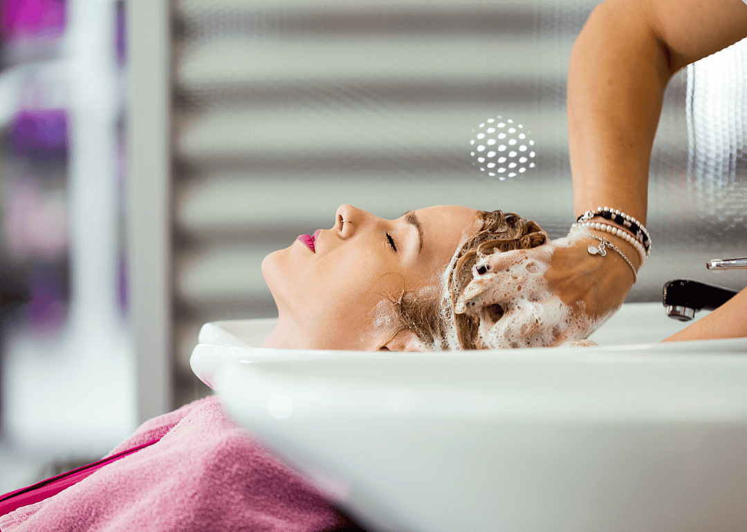 A woman getting her hair washed by a shampooer.