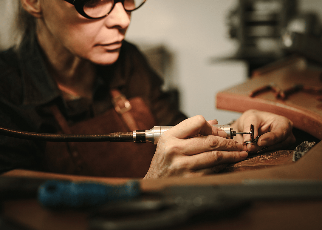 A worker polishes a piece of metal by hand