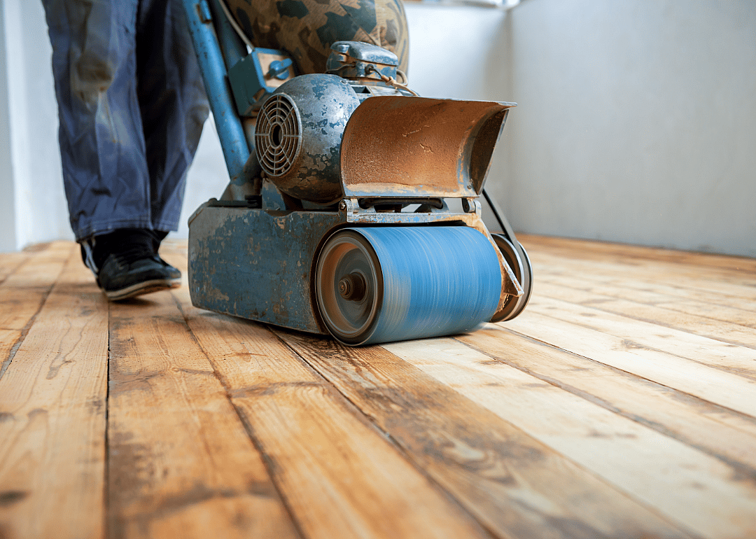 A worker sands a wood floor