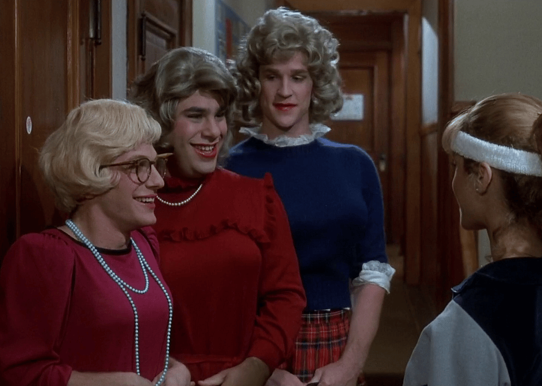 Three guys dressed as women talking to a girl.