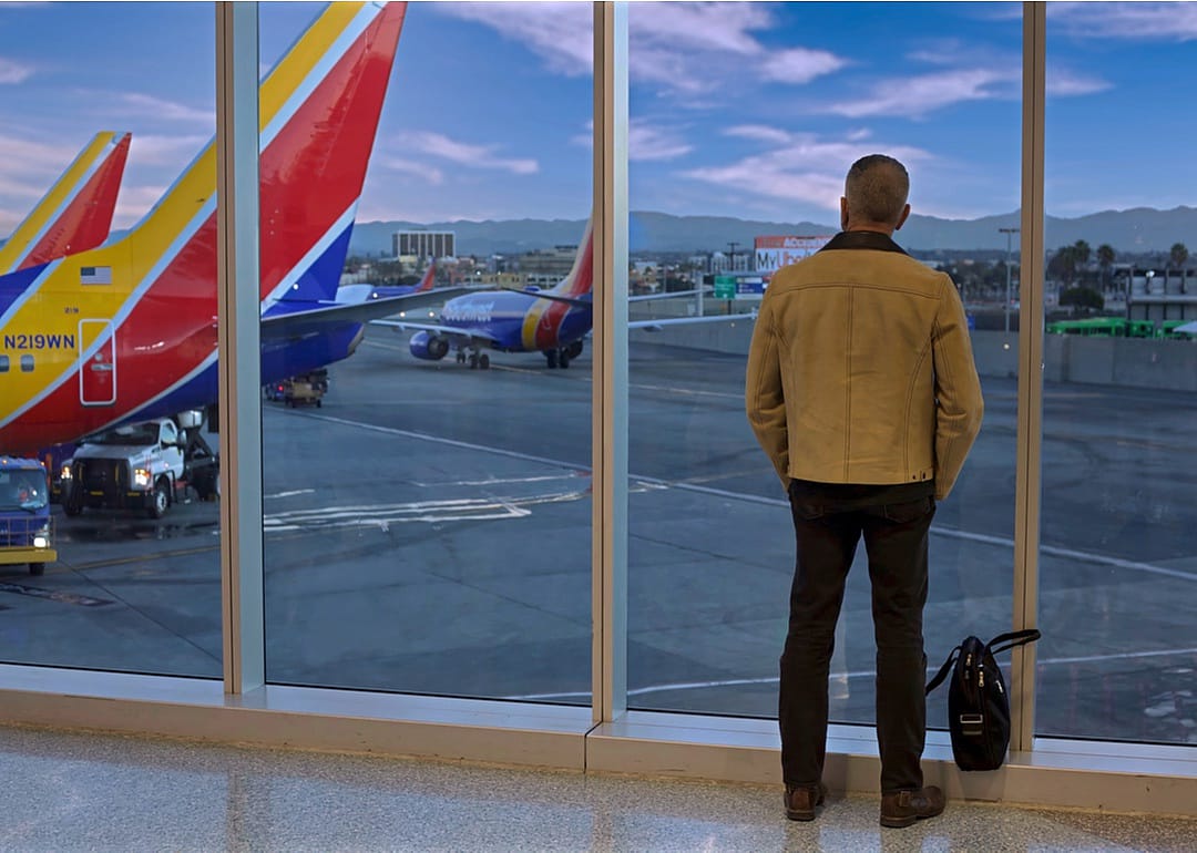 A man watches planes from a Southwest Airlines departure gate window.