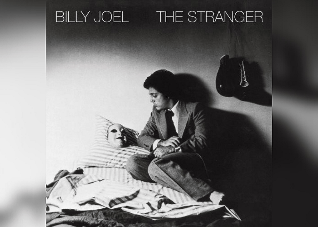 Billy Joel in a bed next to a mask on a pillow.
