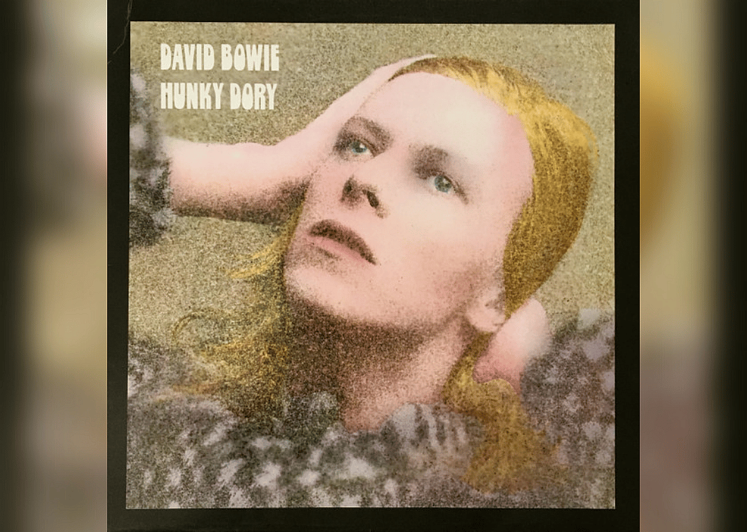 David Bowie looking upward holding his head.