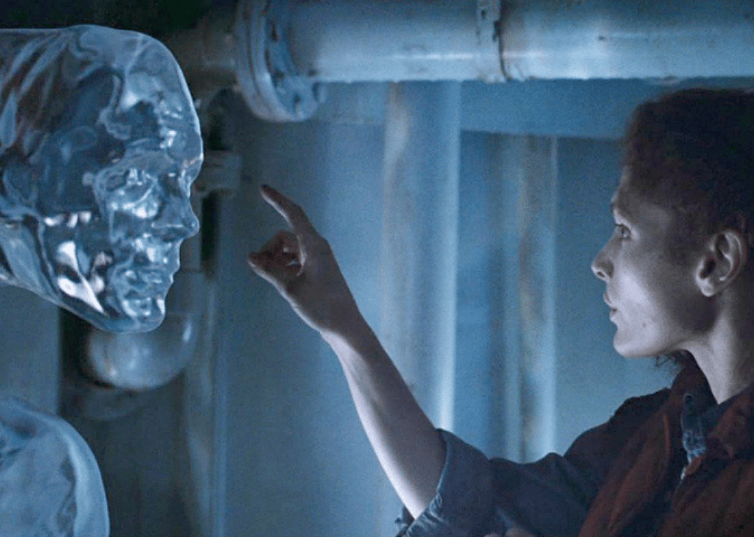 A woman leans in to touch a clear liquid being.