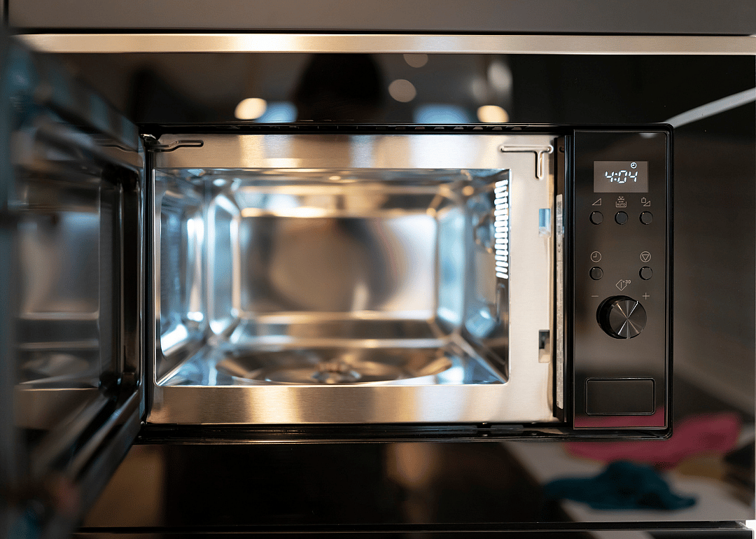 Black microwave with door open and silver inside.