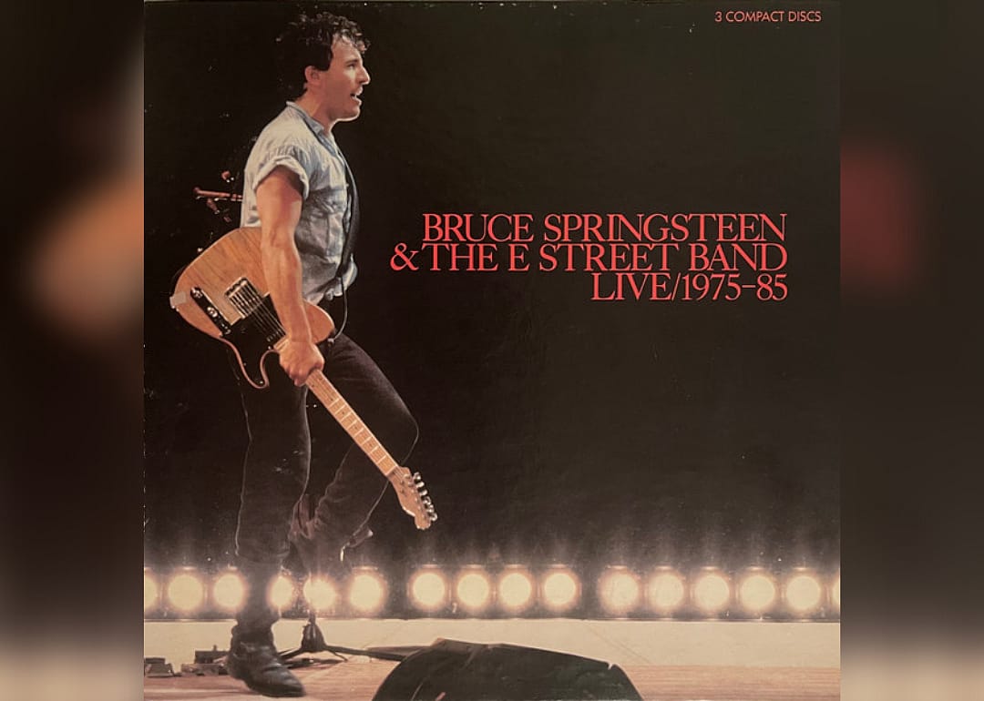 Bruce Springsteen onstage dancing with a guitar.